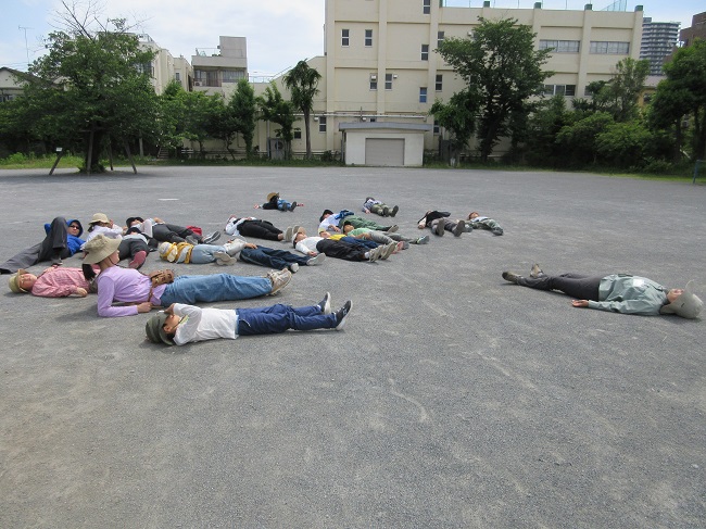 校庭で寝転がりながら行ってみたい場所の空をイメージしている様子
