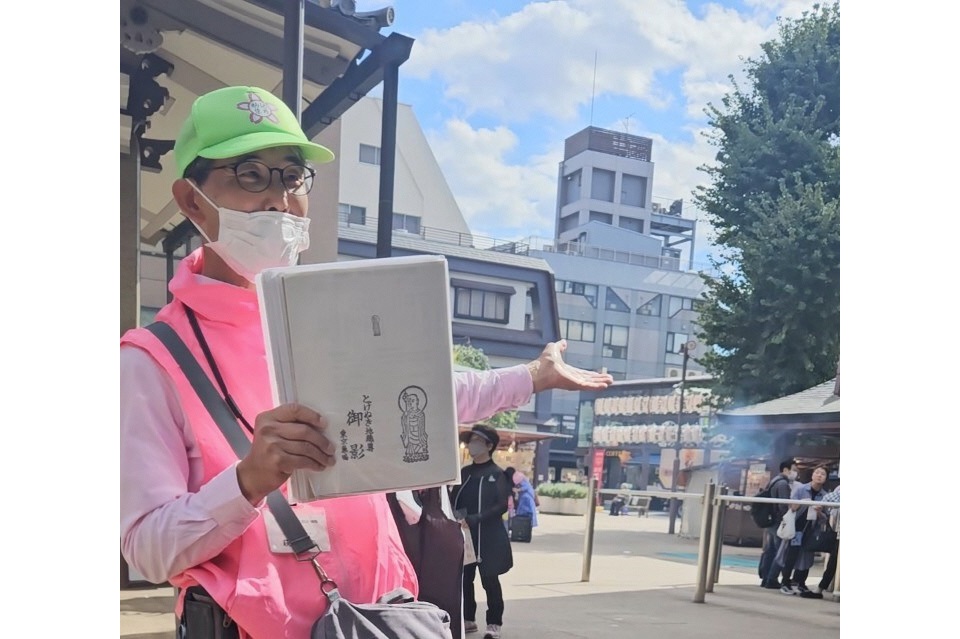 お地蔵尊のガイドブックを持つガイドさんとしま案内人駒込巣鴨